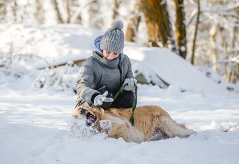 Wall Mural - Teenage Girl Plays With Golden Retriever In Snowy Forest, Sitting With Dog