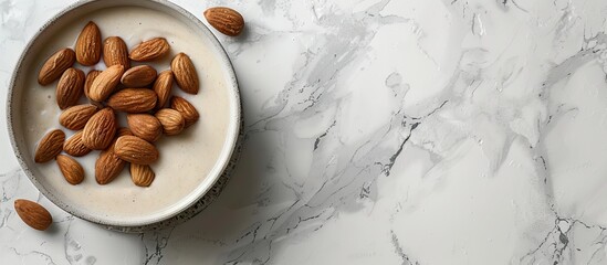 Poster - Homemade almond milk and raw almonds in a wooden bowl in the sink against a white background with selective focus The idea of healthy eating Copy space