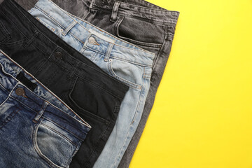 Wall Mural - Assortment of different jeans on a yellow background. Top view. Copy space