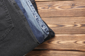 Wall Mural - Stack of Many jeans pants on wooden background. Top view.