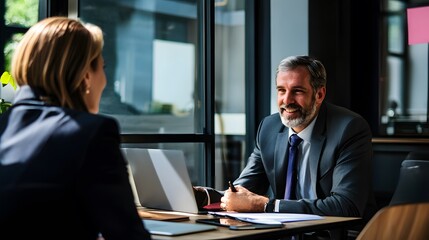 A businessman smiles at a woman in a business meeting.