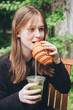 © ADDICTIVE STOCK - Teenage girl eating a croissant and drinking an iced matcha