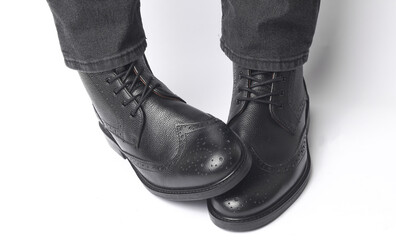 Poster - Male legs in black leather brogue boots on a white background