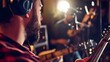 © Felippe Lopes - A bearded man in a red flannel shirt plays guitar in a dimly lit recording studio.