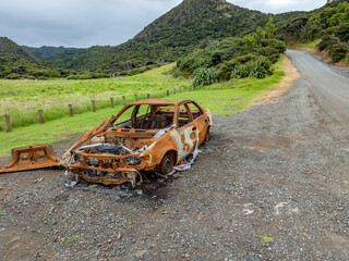 burnt out car wreck abandoned on the side of the road