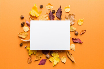 Wall Mural - autumn composition with paper blank and dried leaves on table. flat lay, top view, copy space