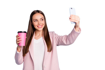 Poster - Portrait of cute cheerful lady using her cellphone making selfie holding mug with hot beverage wearing pink coat isolated over blue color background