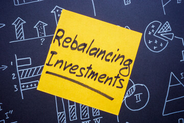 Business charts and a sticky note with rebalancing investments. Financial strategy and portfolio management.
