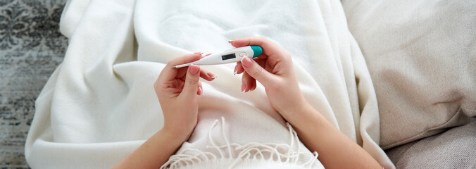 Woman holding a digital thermometer. Concept of fever, flue, virus and quarantine 