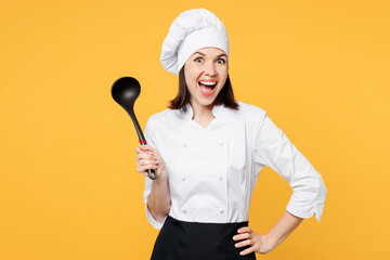 Wall Mural - Young happy cool chef cook baker woman in white shirt apron uniform toque chefs hat hold in hand soup black ladle dipper look camera isolated on plain yellow background studio. Cooking food concept.