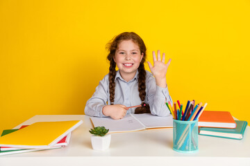 Sticker - Portrait of little schoolchild girl desktop raise arm wave wear uniform isolated on yellow color background