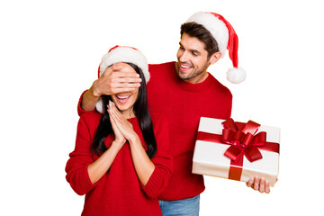 Canvas Print - Portrait of handsome man with brown hair hide his excited wife eyes give her package wear red pullover isolated over yellow background