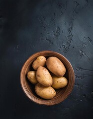 Wall Mural - potato in a bowl on a black background, top view, copy space