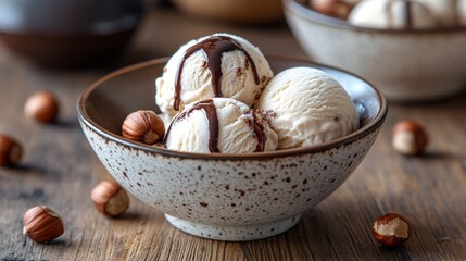 Bowl of vanilla ice cream with chocolate sauce and hazelnuts.