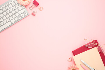 Wall Mural - Office desk table with supplies, computer keyboard, paper notebooks, clips, pens, flowers on pastel pink background.
