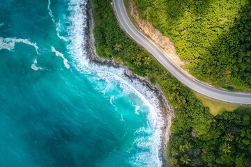 Wall Mural - An aerial view of a winding coastal road, with turquoise waves crashing against the shore and the contrast between land and sea sharply defined. 