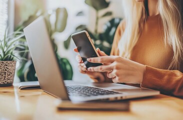 Poster - Close-up of a young Asian businesswoman using her mobile smart phone while she is working on her laptop computer at a modern office setting.