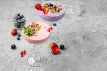 Wall Mural - Different tasty yogurts with fresh berries and granola in glasses on gray textured table, space for text