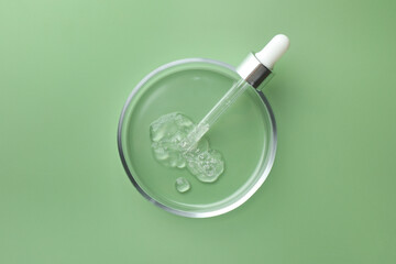 Poster - Petri dish with cosmetic product and pipette on green background, top view