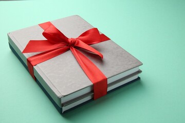 Wall Mural - Books tied with red ribbon on green background, closeup. Perfect gift