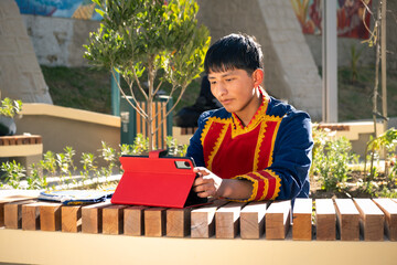 latino teenager in colorful clothes using a tablet in a public park in latin america - social media concept