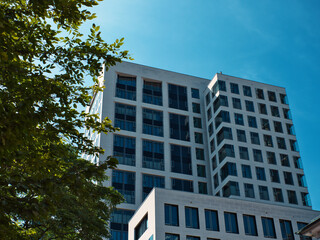 apartment high-rise with a white facade under a clear blue sky and a bit of green in the foreground