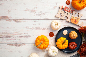Wall Mural - Flat lay composition with plaid, plate with pumpkins, Hello Fall message on wooden desk table top view.
