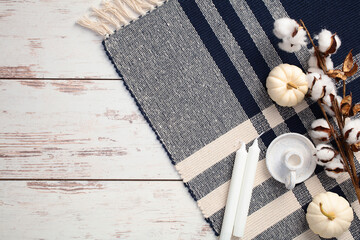 Wall Mural - Cozy home desk table with plaid, white pumpkins, cotton, candles on rustic wooden table. Autumn, fall or winter holidays concept.