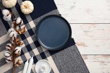 Wall Mural - Empty blue ceramic plate, white pumpkins, candles, cotton on plaid on rustic wooden table. Hygge, cozy home desk, top view.