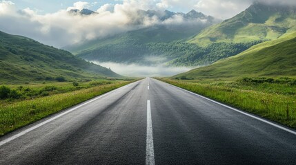 Wall Mural - Smooth asphalt road leading to green, misty mountains with morning clouds overhead, evoking a peaceful drive.