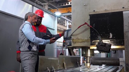 Wall Mural - Production Manager Talking To African American CNC Machine Operator - Zoom In Shot. Multiracial Industrial Coworkers. Production Manager Using Digital Tablet. CNC Milling Machine Tool Processes Steel.