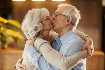 Wall Mural - Romantic senior couple hugging and kissing at cozy home.