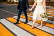 © Mariakray - Caucasian couple holding hands crossing city intersection