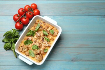 Poster - Tasty baked cauliflower in baking dish, basil and tomatoes on light blue wooden table, top view. Space for text