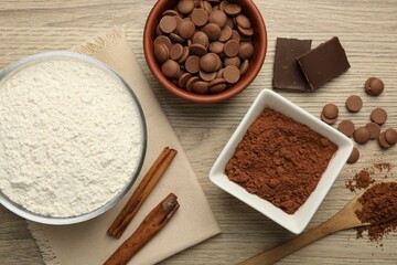 Flour, chocolate and cocoa for making dough on wooden table, flat lay