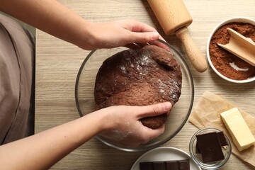 Canvas Print - Woman kneading chocolate dough at wooden table, top view