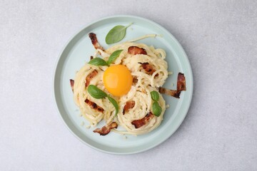 Sticker - Delicious pasta Carbonara with egg yolk, bacon and basil on light gray table, top view