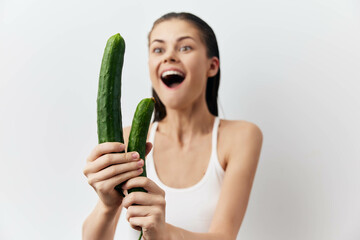 Canvas Print - Excited woman holding cucumbers in front of a plain white background, showcasing a fun and playful concept of healthy eating or gardening Her expression is joyful and surprised, illuminating freshness