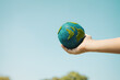 © InfiniteFlow - Young boy's hand holding planet Earth globe with sky and cloudscape background as Earth day to save this planet with ESG principle and environment friendly energy for brighter future. Gyre