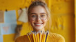 © Aliaksandra - a mischievously smiling woman holds a bouquet of sharpened pencils in a whimsical back-to-school concept with a touch of humor