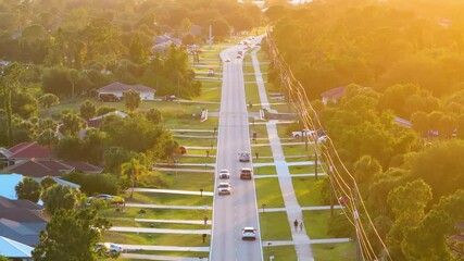 Sticker - Rural road with driving traffic cars in American small town in Florida. Private homes between green trees and suburban streets in quiet residential area.