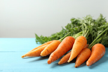 Tasty ripe juicy carrots on light blue wooden table, closeup