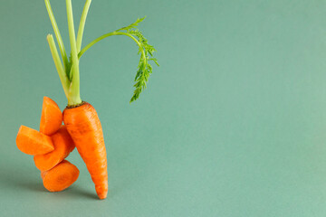 Wall Mural - Whole and cut fresh carrots on green background, space for text