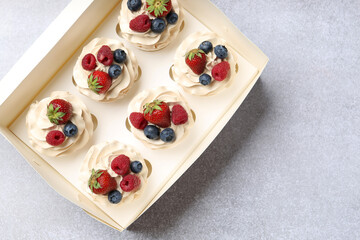 Poster - Tasty cupcakes with different berries in box on light grey table, top view. Space for text