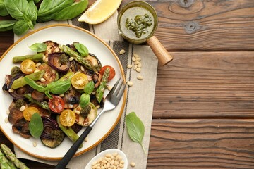 Poster - Delicious salad with grilled vegetables, basil, pesto sauce, pine nuts and fork on wooden table, flat lay. Space for text