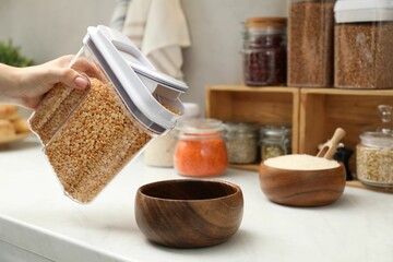 Canvas Print - Woman putting peas from container into bowl at light marble countertop in kitchen, closeup