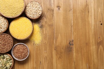 Sticker - Different types of seeds and cereals in bowls on wooden table, flat lay. Space for text