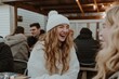 © Dmitrii - A woman wearing a cozy sweater and hat laughs joyfully while enjoying time with friends at a winter gathering
