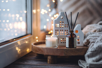 Wall Mural - Aroma diffuser, burning candle, Christmas perfume on wooden bamboo tray, knitted sweater. Cozy home decor, hygge and aromatherapy concept. Comfortable atmosphere, Scandinavian decor.