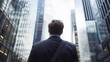 © Vagner Castro - An office worker standing with his back turned in front of a tall building, seen from a low angle. Concept of the grandeur of the building symbolizing the pinnacle of one's career.